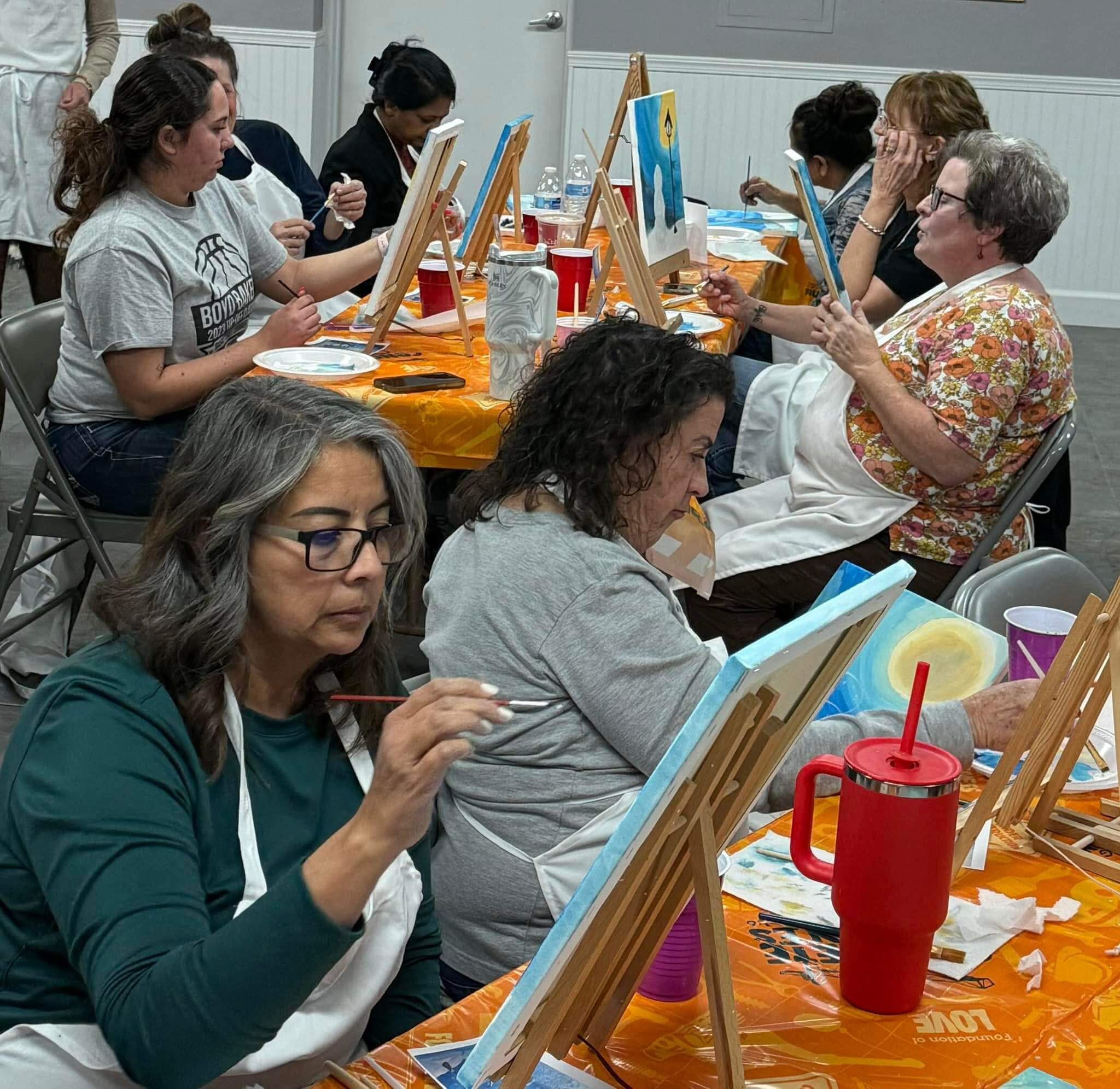 Paint night attendees concentrate on their easels